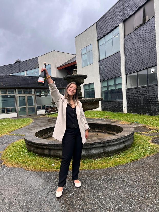 Estudiante celebrando afuera de su universidad tras aprobar
