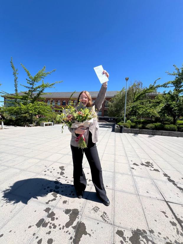 Estudiante celebrando con flores tras su titulación